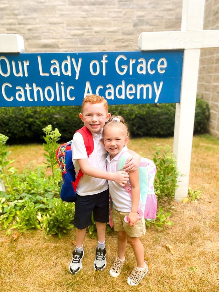 Grace students posed in front of the school sign