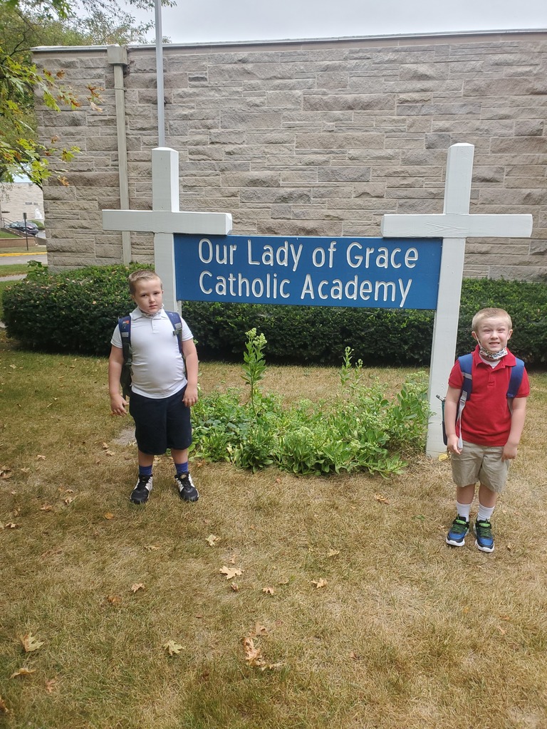 Green brothers posed in front of school sign.