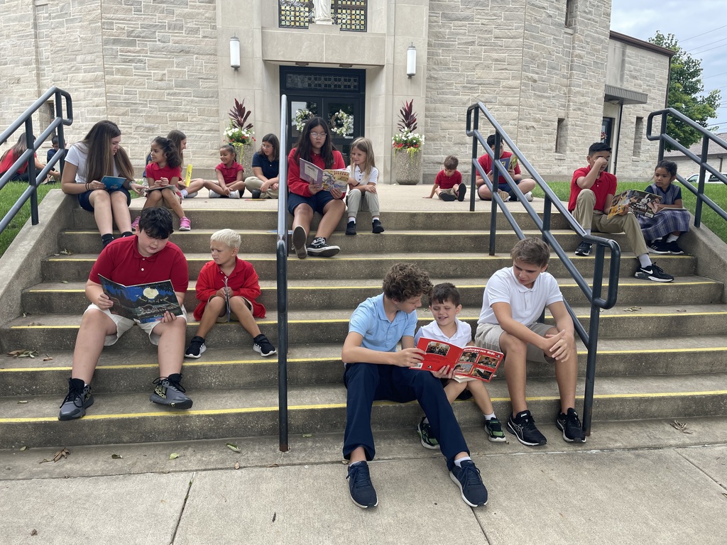 Kindergarteners and their 7th/8th grade buddies begin their weekly “read together” on the church steps.